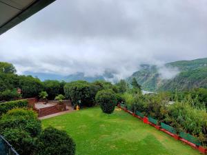 a green yard with trees and mountains in the background at Bella Vista Mahabaleshwar in Mahabaleshwar