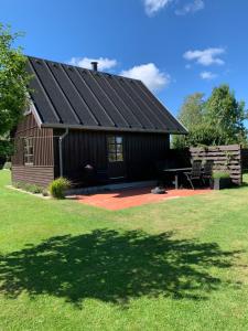 un granero con techo negro y mesa de picnic en Hytten, en Ålbæk