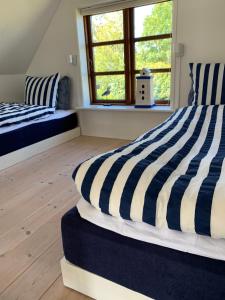 1 dormitorio con 2 camas con rayas azules y blancas en Hytten en Ålbæk