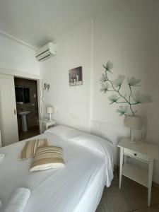 a white bedroom with a bed and a plant on the wall at Book and Bed in Maglie