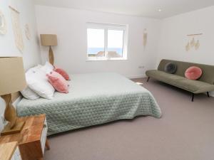 a bedroom with a bed and a couch and a window at Sandy Cove in Penzance