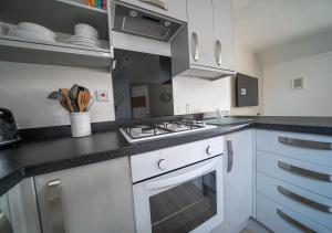 La cuisine est équipée de placards blancs et d'un four avec plaques de cuisson. dans l'établissement The Cosy Apartment Sherburn in Elmet, à Sherburn in Elmet