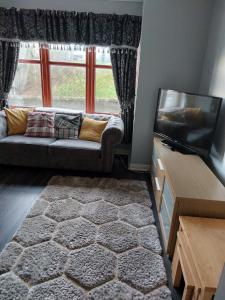 a living room with a couch and a tv at Stewarton apartments in Stewarton