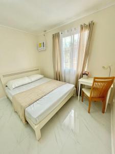 a bedroom with a bed and a chair and a desk at AIRPORT GUESTHOUSE DAVAO in Davao City