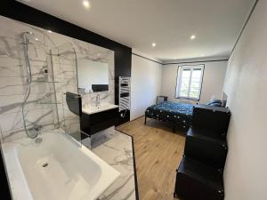 a bathroom with a tub and a sink and a bed at Le Champ Du Possible in Uxeau