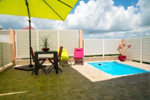 une terrasse avec une table, un parasol et une piscine dans l'établissement Villa d'une chambre a Les Trois Ilets a 500 m de la plage avec piscine privee jardin clos et wifi, à Les Trois-Îlets