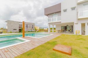 un patio trasero con piscina y una casa en SA06 Excelente Casa 5 Quartos - Reserva de Sauípe en Costa do Sauipe