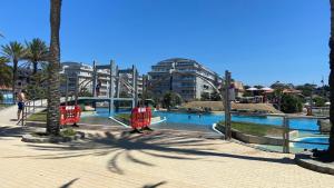 a swimming pool in a city with palm trees and buildings at Apartamento Playa Samil in Vigo