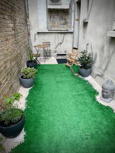 un patio con césped verde, plantas y una mesa en Suites Mana - Le Manaloft ****, en Rethel