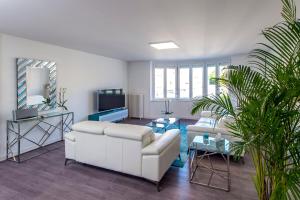 salon z białą kanapą i telewizorem w obiekcie Suites Mana - Le Manaloft, Chic et moderne avec salle privée de Fitness en plein centre-ville de Rethel w mieście Rethel
