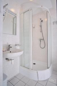 a white bathroom with a shower and a sink at Hotel Pernigele in Jelgavkrasti