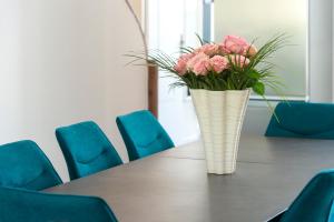 un jarrón de flores rosas sentado en una mesa en Suites Mana - Le Manaloft ****, en Rethel