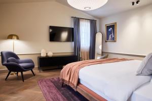 a bedroom with a bed and a chair and a television at Martis Forum Heritage Hotel & Residence in Poreč