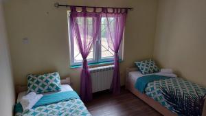 a bedroom with two beds and a window with purple curtains at Vila Largo in Donja Mala