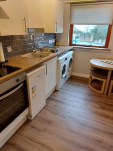 a kitchen with a sink and a washing machine at Stewarton apartments in Stewarton