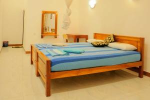 um quarto com uma cama de madeira com lençóis e almofadas azuis em Julia Safari Inn em Tissamaharama