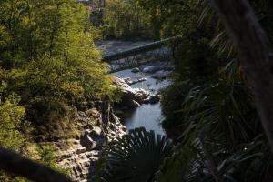 un puente sobre un río con rocas y árboles en Ristorante della Stazione, en Tegna