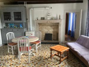 een woonkamer met een tafel en stoelen en een open haard bij Country Homes Gite 2 in Saulgé