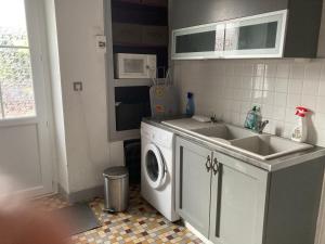 een keuken met een wastafel en een wasmachine bij Country Homes Gite 2 in Saulgé