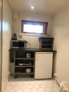 a small kitchen with a microwave and a refrigerator at Basement Apartment Varadero in Lyngdal