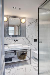 Baño de mármol con lavabo y espejo en Martis Forum Heritage Hotel & Residence en Poreč