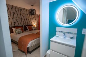 - une chambre avec un lit, un lavabo et un miroir dans l'établissement Chambre Jungle dans maison d'hote "Le Petit Clouet"- Rochecorbon, à Rochecorbon