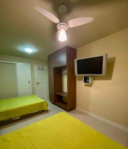1 dormitorio con 1 cama y TV de pantalla plana en apart-hotel Golden Lake, en Arraial do Cabo