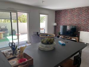 ein Wohnzimmer mit einem Tisch und einem TV in der Unterkunft Appartement avec terrasse proche de Rennes in Saint-Jacques-de-la-Lande