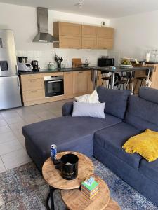 een woonkamer met een blauwe bank en een tafel bij Appartement avec terrasse proche de Rennes in Saint-Jacques-de-la-Lande