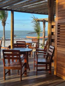 een houten terras met tafels en stoelen op het strand bij VILLA ÁGUA DE COCO PREÁ in Prea