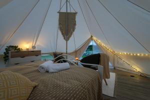 ein Schlafzimmer in einem Zelt mit einem Bett und einem Stuhl in der Unterkunft Glempings Laimes Taure in Vabole