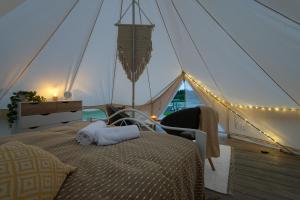 a bedroom in a tent with a bed and a chair at Glempings Laimes Taure in Vabole