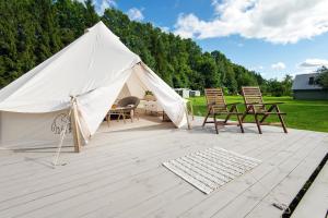 a large white tent with chairs on a patio at Glempings Laimes Taure in Vabole