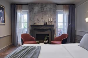 a bedroom with a bed and two chairs and a fireplace at Martis Forum Heritage Hotel & Residence in Poreč