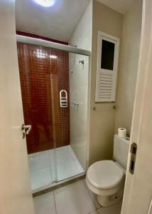 y baño con aseo y ducha acristalada. en apart-hotel Golden Lake, en Arraial do Cabo