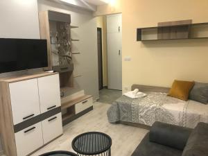 a living room with a bed and a flat screen tv at Sunrise City A2, Sarafovo in Burgas