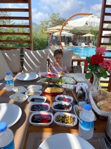a child sitting at a table with plates of food at Güven Park Residance & Hotel in Kemer