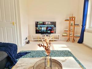 ein Wohnzimmer mit einem TV und einer Vase mit Blumen. in der Unterkunft Homely Three Bed Holiday Home in Glasgow in Glasgow