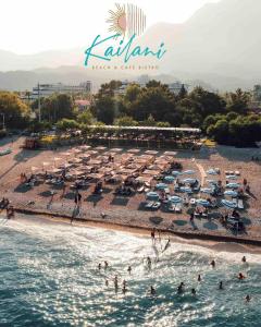 a beach with umbrellas and people in the water at Güven Park Residance & Hotel in Kemer