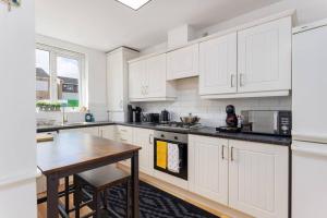a kitchen with white cabinets and a wooden table at Sunshine Terrace by Happy Sunshine Stay in Manchester