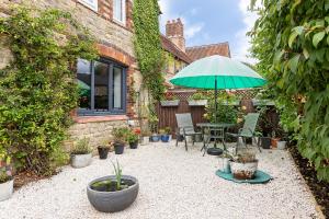 eine Terrasse mit einem Tisch und einem Sonnenschirm in der Unterkunft Village Retreat & Hot Tub Nr Bicester Village in Bucknell