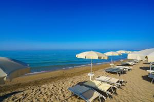 um grupo de cadeiras e guarda-sóis numa praia em Sikania Resort & Spa em Licata