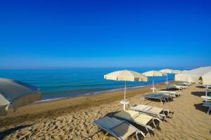 eine Gruppe von Stühlen und Sonnenschirmen am Strand in der Unterkunft Sikania Resort & Spa in Licata
