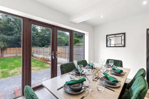 comedor con mesa de madera y sillas verdes en Walsall - 4 Bedroom House, Wi-Fi, Garden , Sleeps 8 - JRR Stays, en Bescot