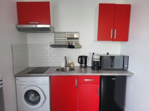 een keuken met rode kasten en een wasmachine bij maisonnette à 10min de disney in Jossigny
