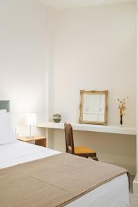 1 dormitorio con cama, espejo y silla en The H Experience - The Good Life Archanes - Free parking, en Archanes