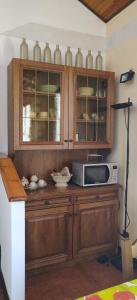 a kitchen with wooden cabinets and a microwave at Appartamento Arcobaleno in Folgaria
