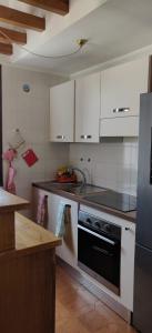 a kitchen with white cabinets and a black oven at Appartamento Arcobaleno in Folgaria