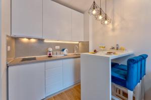 a kitchen with white cabinets and a blue chair at Hugo Apartmani Zlatibor in Palisat