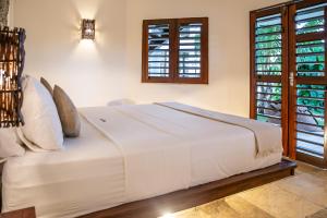 Cama blanca en habitación con ventanas en Windtown Beach Hotel en Cumbuco